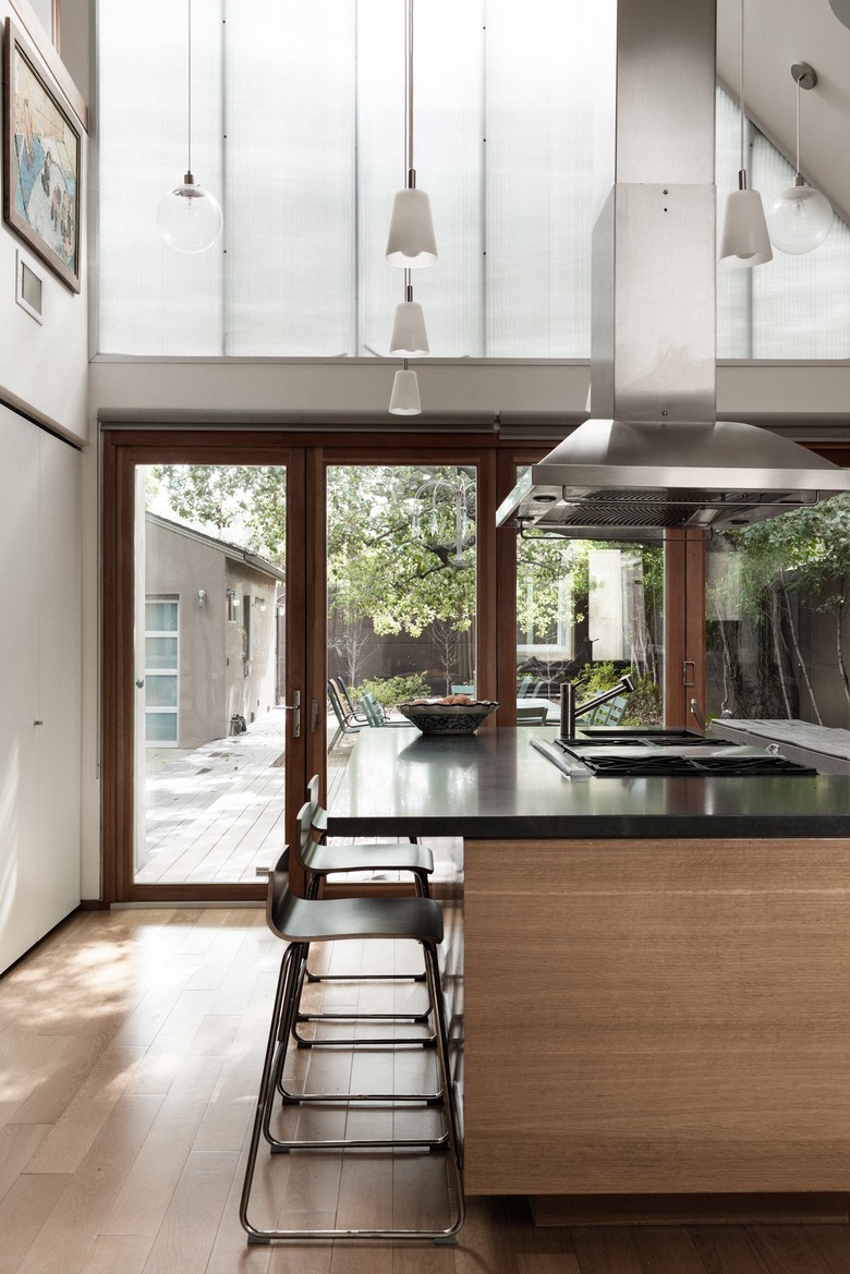 Large wood and black kitchen island with range and suspended vent hood