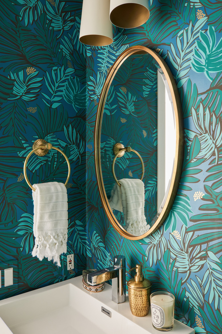 tropical wallpaper in a powder room with brass fixtures