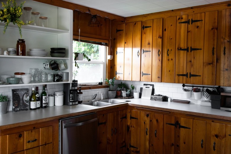 A kitchen with wood cabinets, white tile backsplash, and white counters.