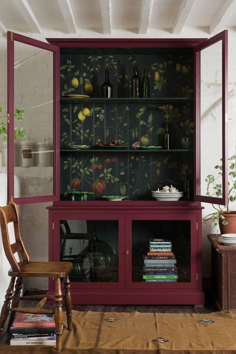 Dark maroon kitchen cabinet, chair, books, plates