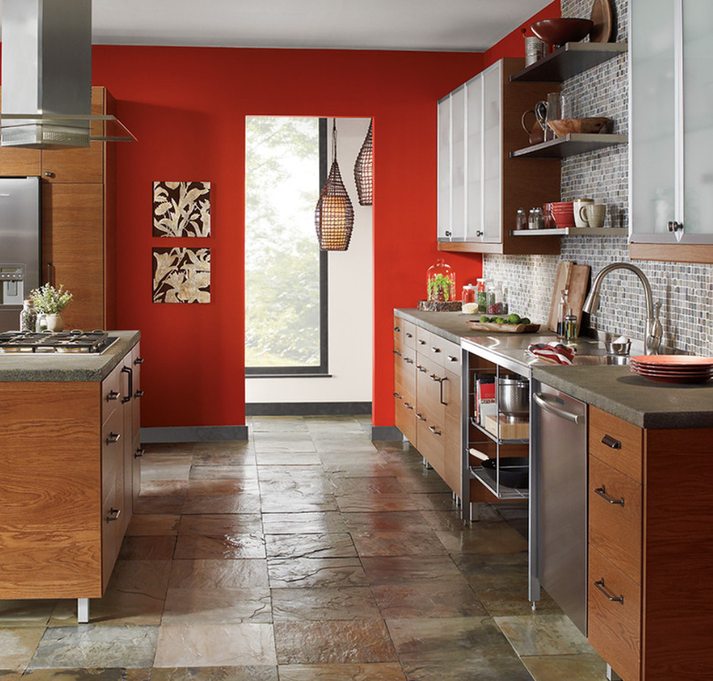 Red painted accent wall in kitchen with wood cabinetry and slate floors.