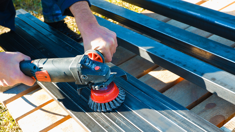 Hand with a turbine removes rust from metal. man using angle grinder