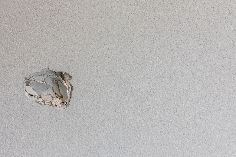 A hole in the wall of a hallways caused by a fist punching through the wall