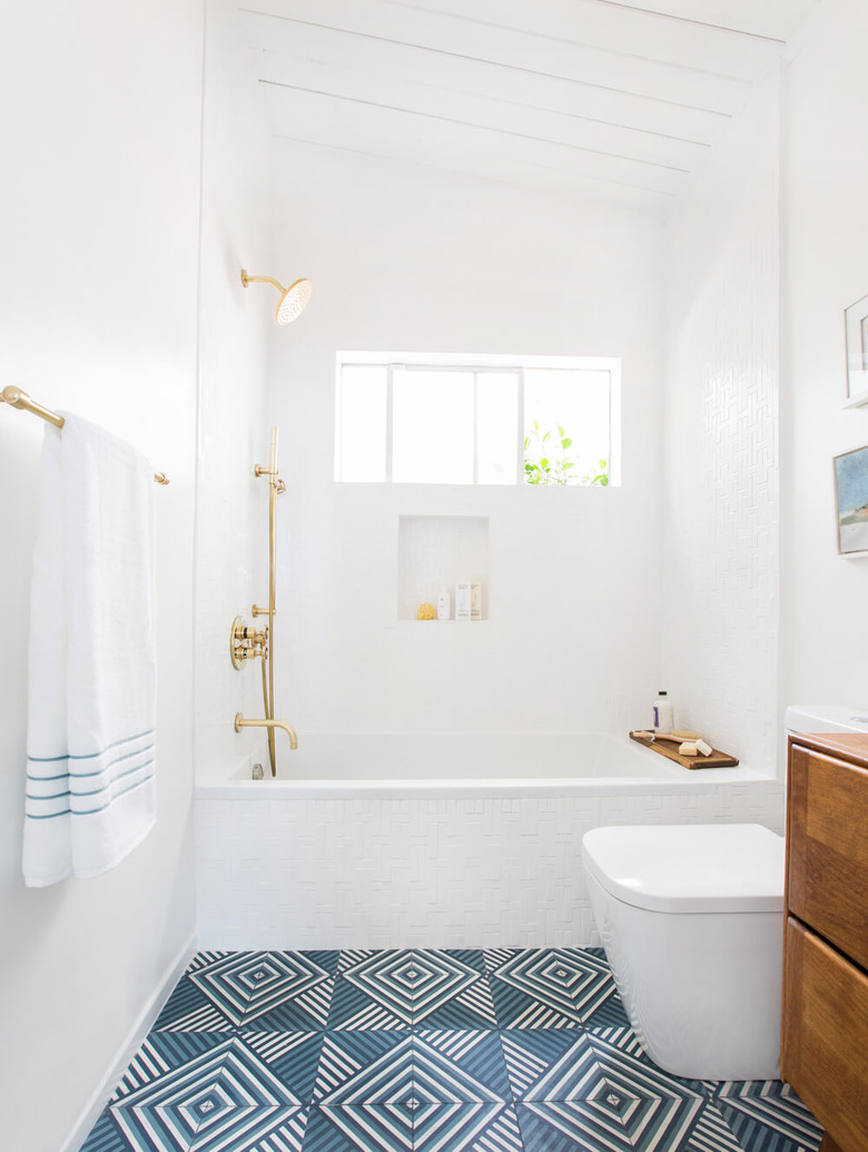 bathroom idea with brass bathroom fittings and patterned floor tile with wood vanity