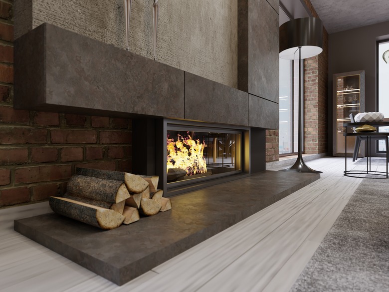 Loft-style designer fireplace, built-in firebox with burning fire and firewood.