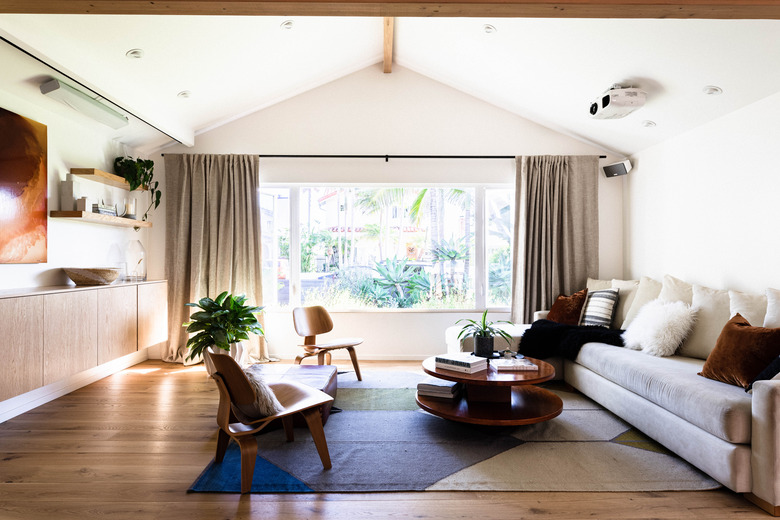 living room with arched ceiling, blue-and-white rug, floating credenza, long taupe couch