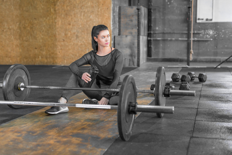 Tired woman sitting in a gym on the floor.