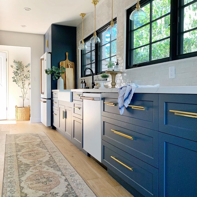 rug for kitchen floor with navy and brass cabinets in eclectic kitchen