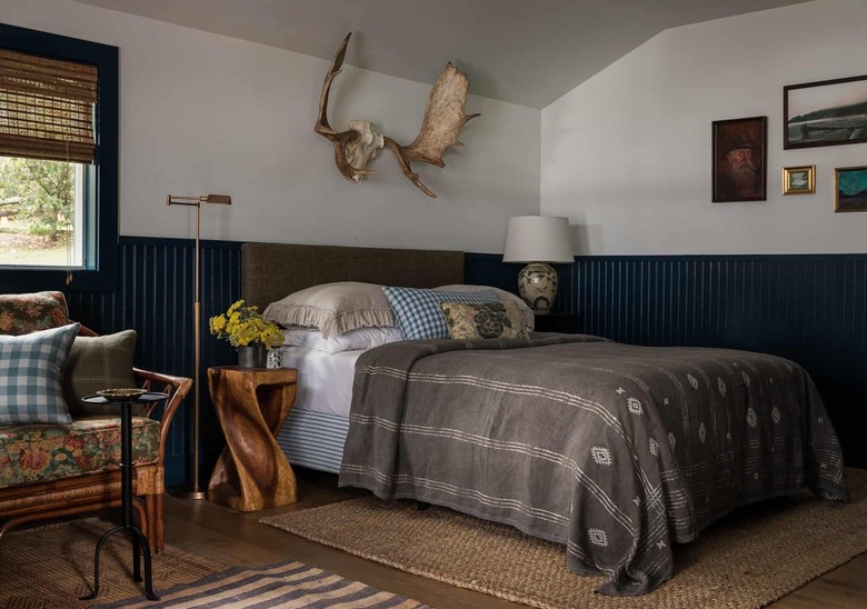 Rustic blue wainscoting in bedroom with antlers above bed