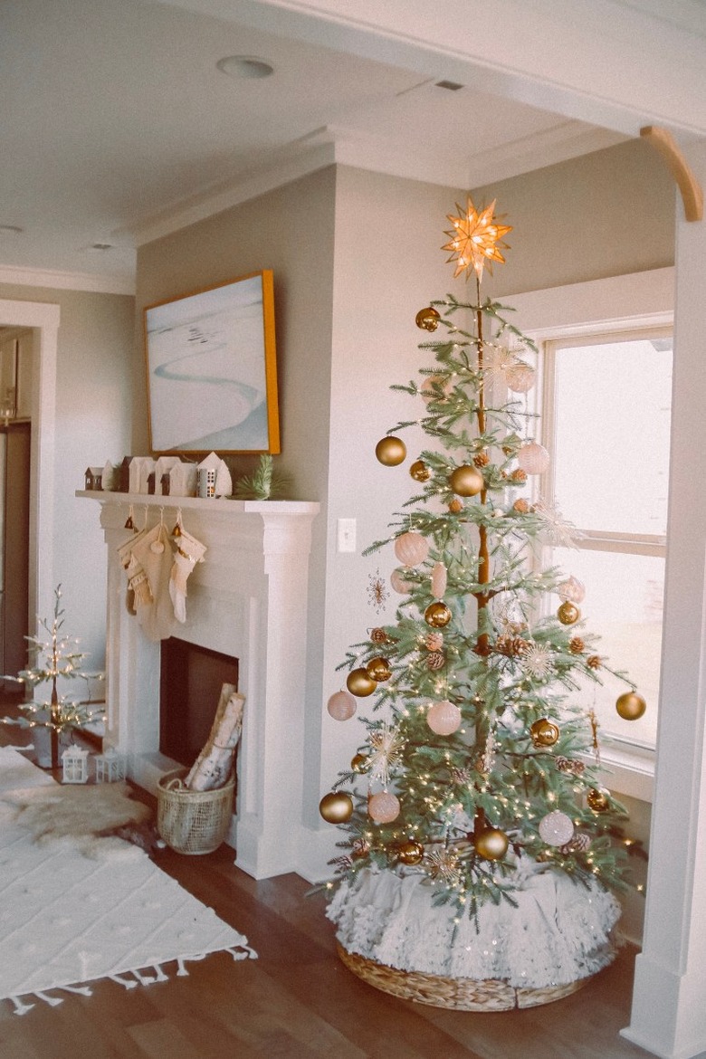 Rustic Christmas tree with white and brown ornaments and woven tree collar