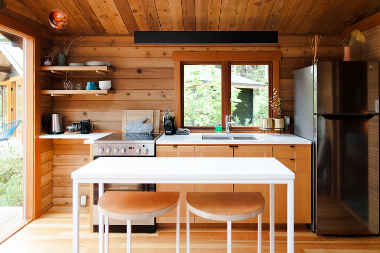 kitchen with white table and stools, rustic walls and cabinets