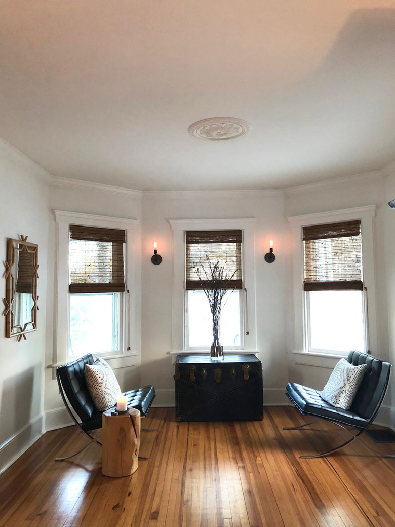 rustic living room lighting idea with wall sconces near windows and Barcelona chairs