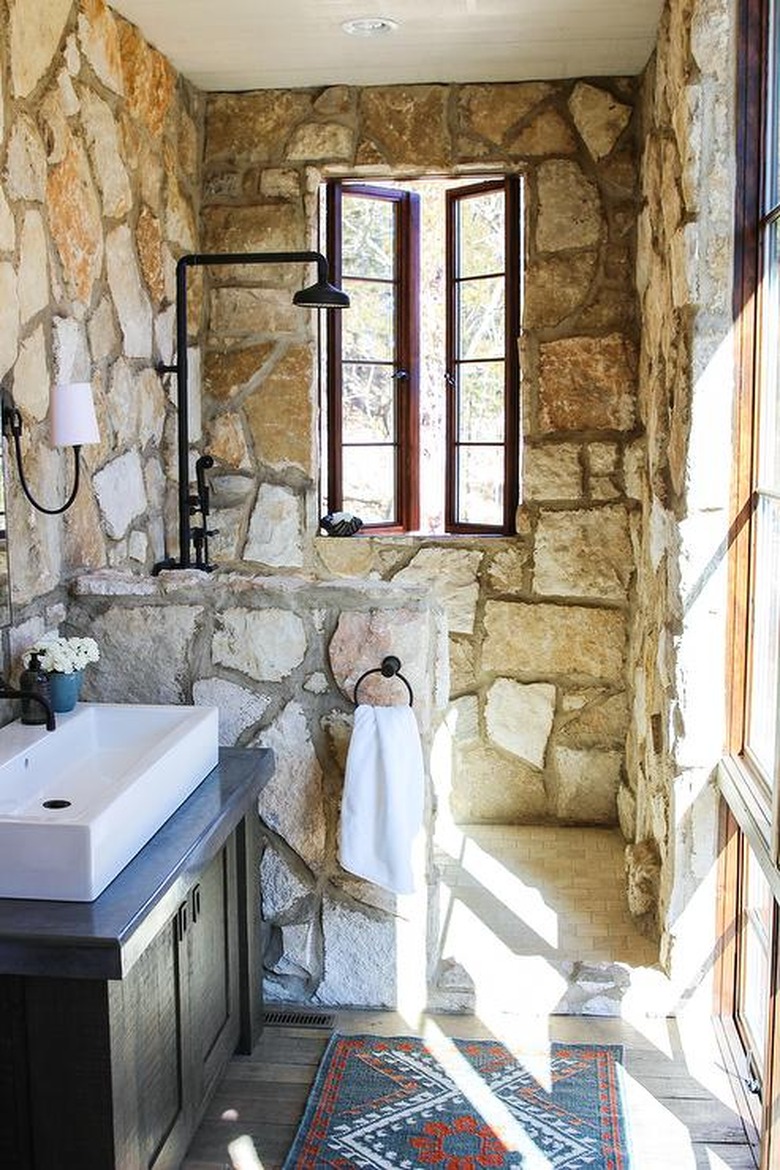 stone rustic shower tile in bathroom with white sink and black fixtures