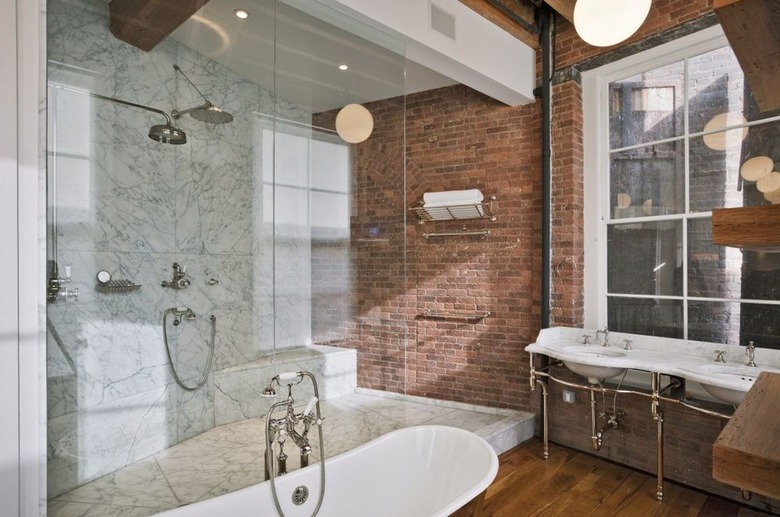 marble rustic shower tile in bathroom with brick wall and wood floor