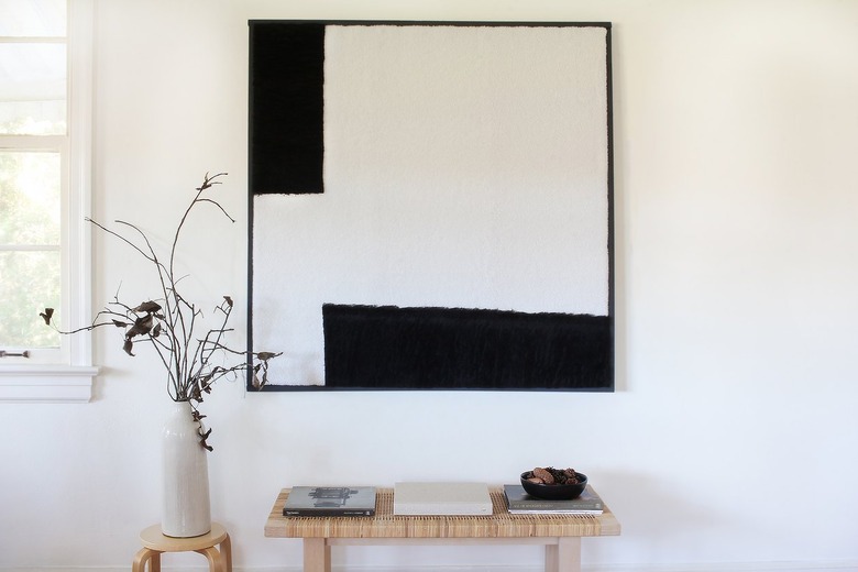 Black and white wall art with bench, stool, and plant