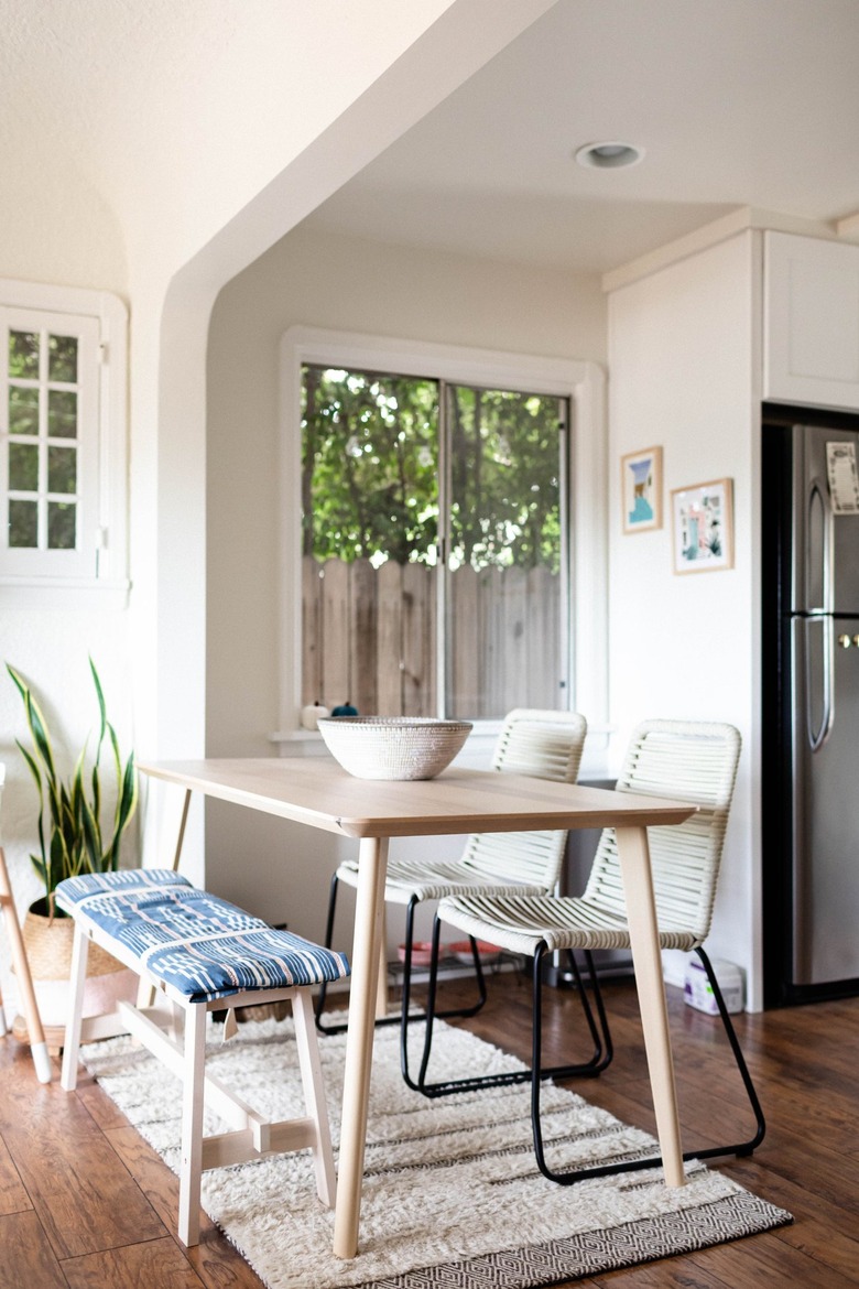 Minimalist dining room with white walls, wood floors and beige dining table