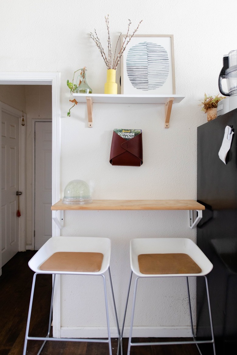 White stools and wood shelving with plants and art