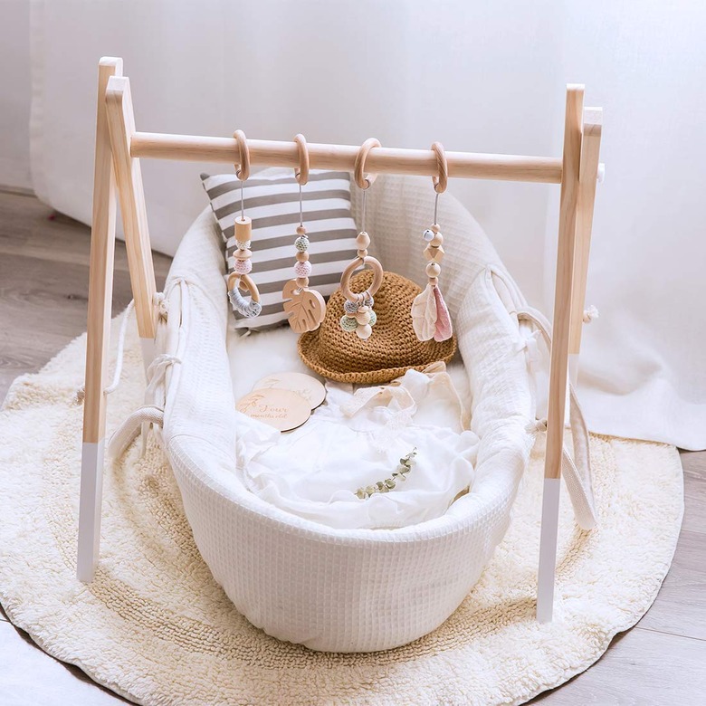 Scandinavian nursery idea with wooden baby gym on floor near window