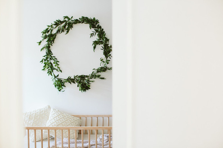 Scandinavian nursery idea with light wood crib and eucalyptus wreath hanging on wall above