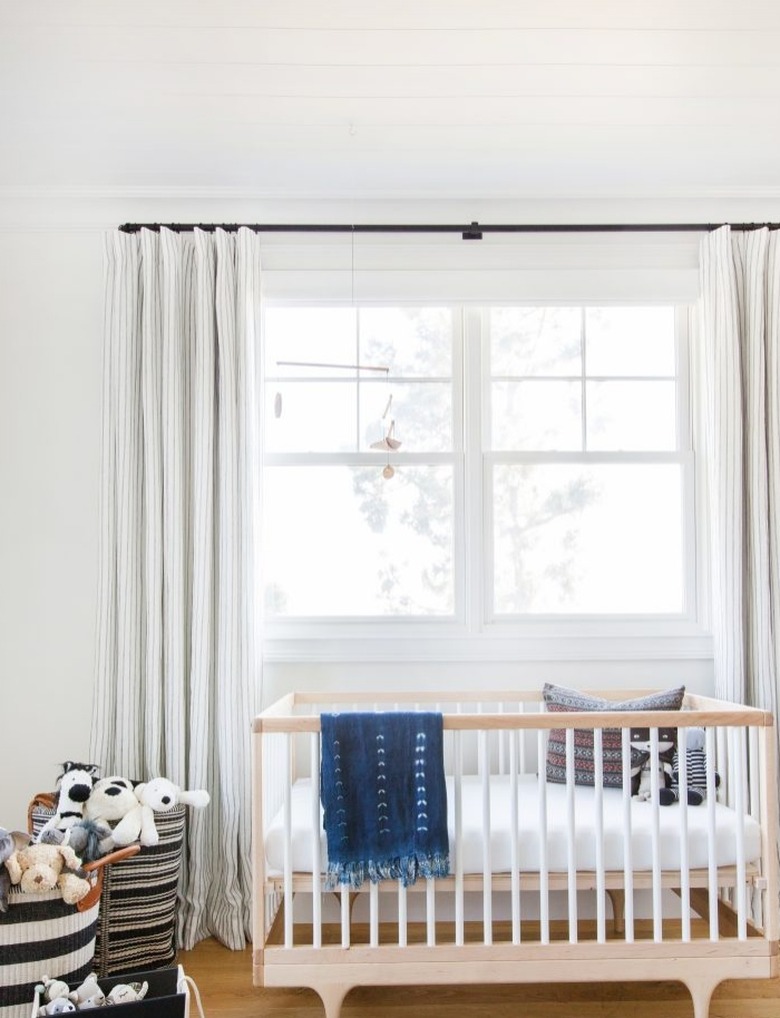 Scandinavian nursery idea with crib in front of window