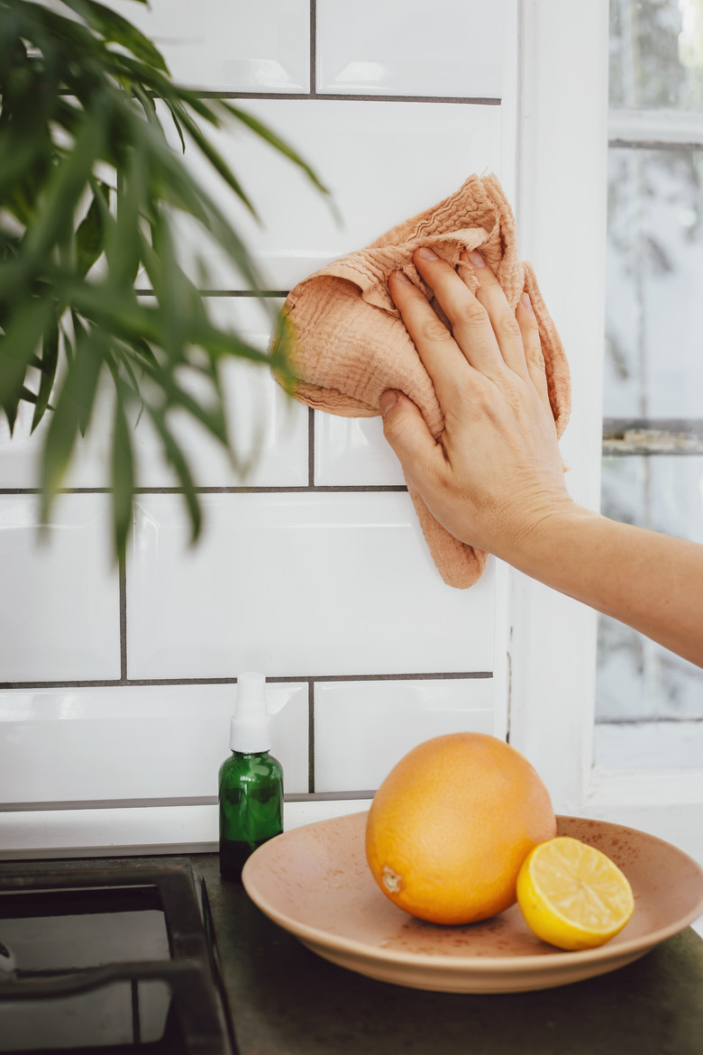 Cleaning kitchen tile with cloth, and lemons