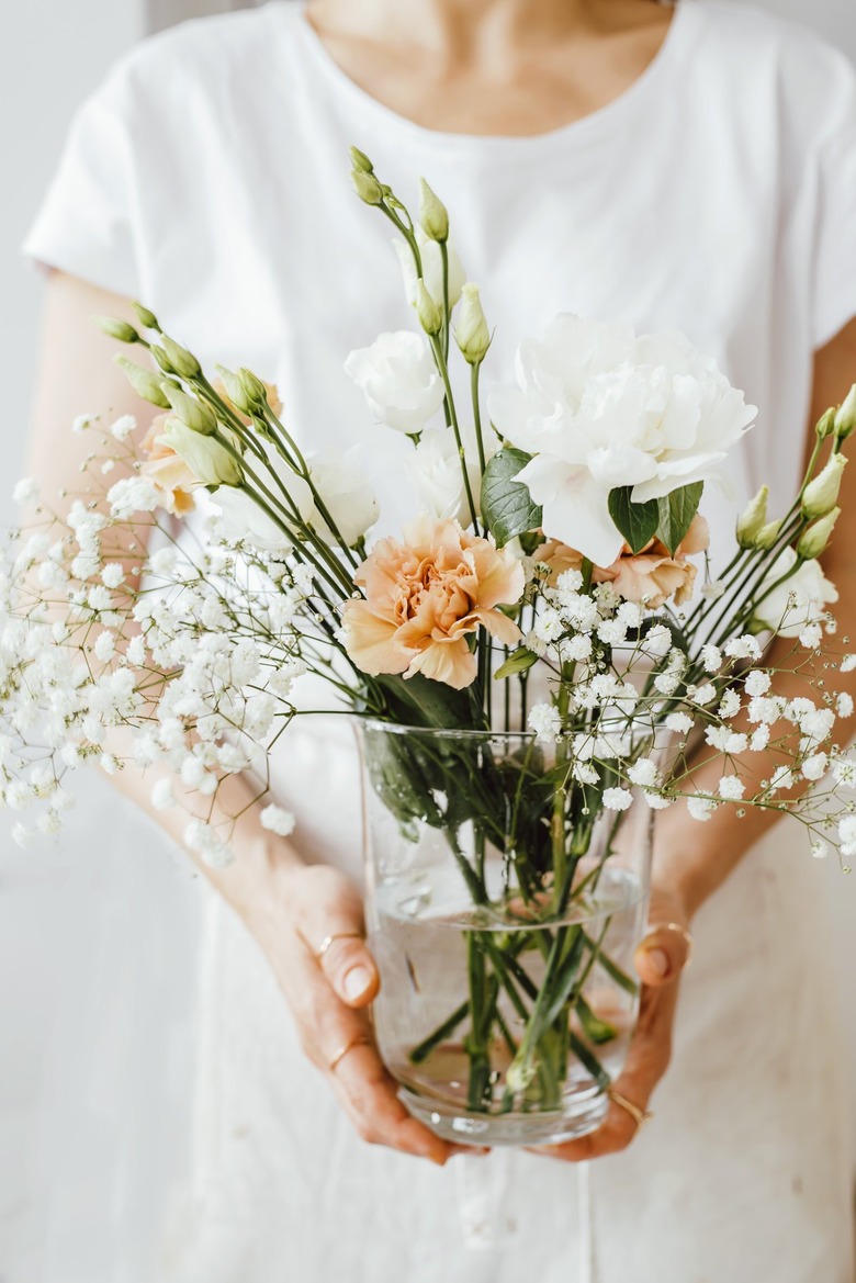 Woman holding flowers in glass vase