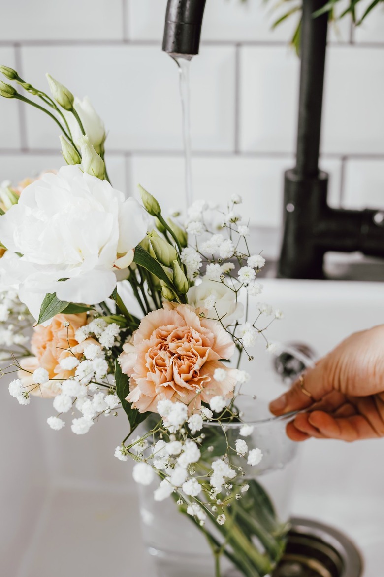 Adding water to glass vase with flowers