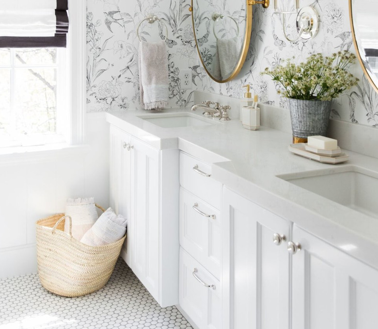 Shabby Chic Bathroom Storage in Bathroom with floral wallpaper, white counter, oval mirrors, basket on floor, towels.