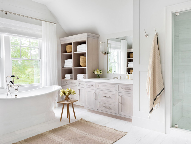 Shabby Chic Bathroom Storage in Bathroom with large tub, built in cabinets and shelves, towels, small stool, flowers, rugs.