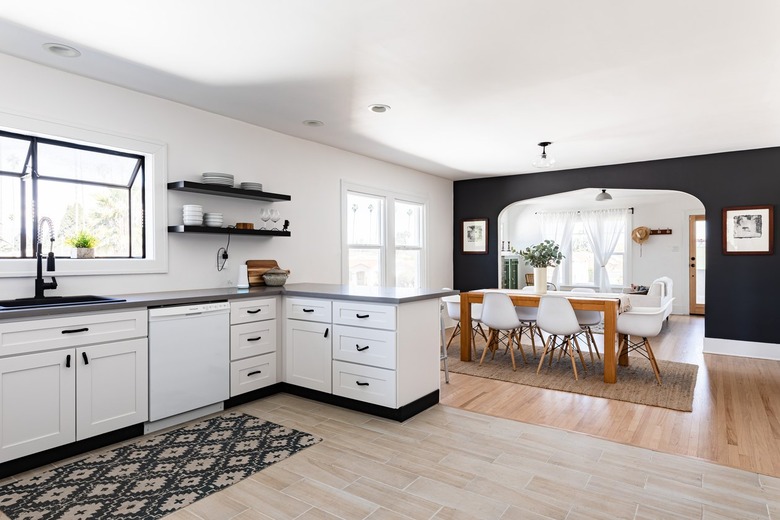 A white kitchen with white-black cabinets and a dining room with wood floors