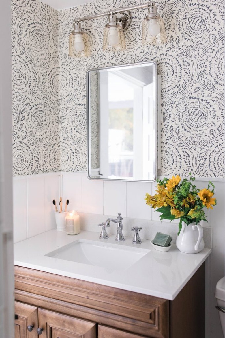 Powder room with shiplap, wallpaper, wood vanity, white counter.