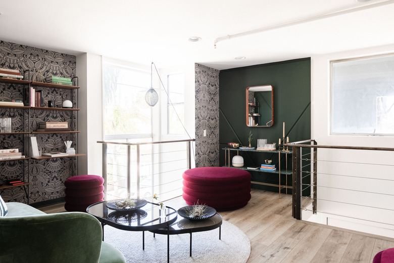 jewel-tone library with patterned wallpaper and green walls with curved furniture