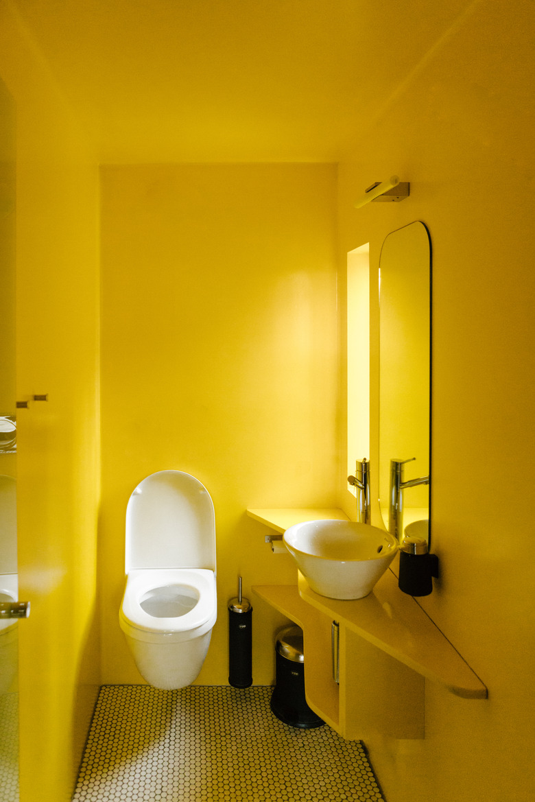 Wall-mounted toilet in yellow painted bathroom