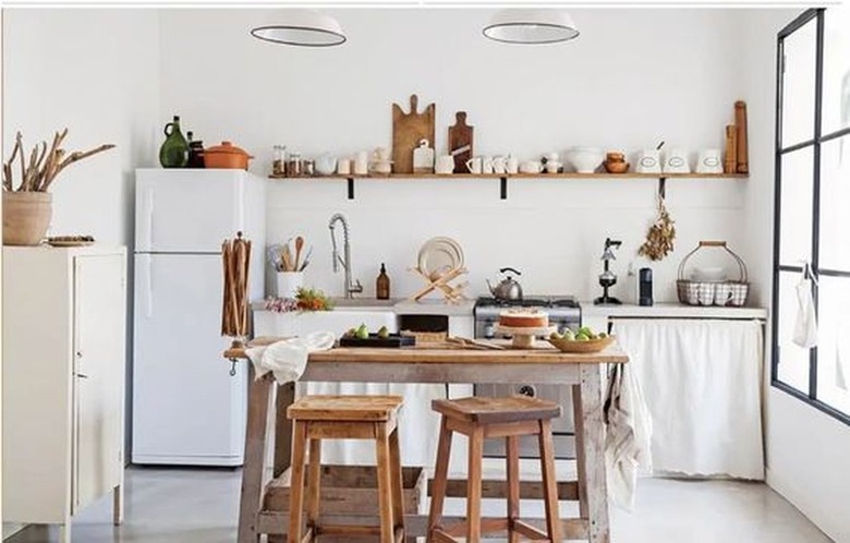 Minimalist white kitchen with linen cabinet curtains and open shelving.