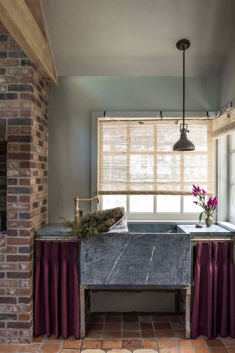 country kitchen with cabinet curtains on either side of large marble sink