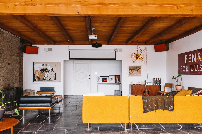 living room with wooden ceilings, yellow couch, slate floor