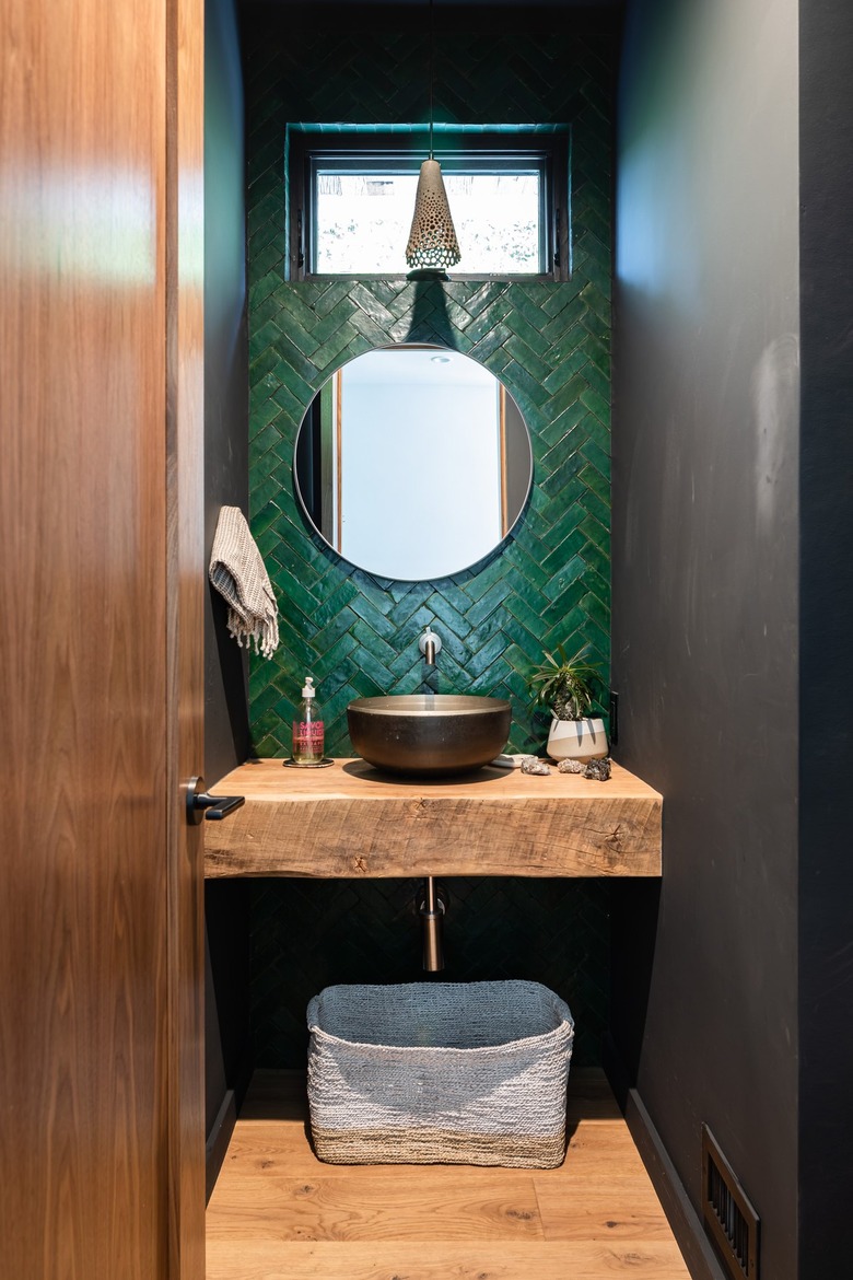 Green tiled bathroom with a wood counter and flooring with small window