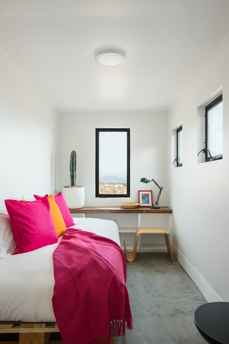 small white painted bedroom with pink blanket and pillows