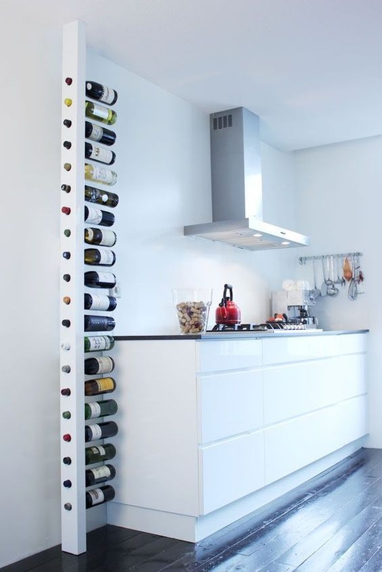 All white kitchen with floor to ceiling wine rack.