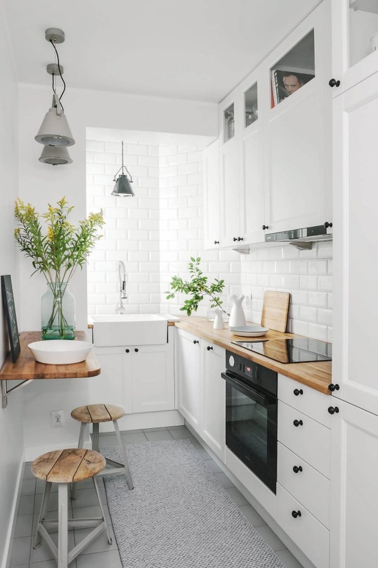 Small kitchen with dining counter, tile backsplash, modern wood chairs.