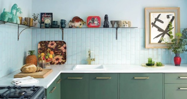 Kitchen with green cabinets, white backsplash, open shelf.