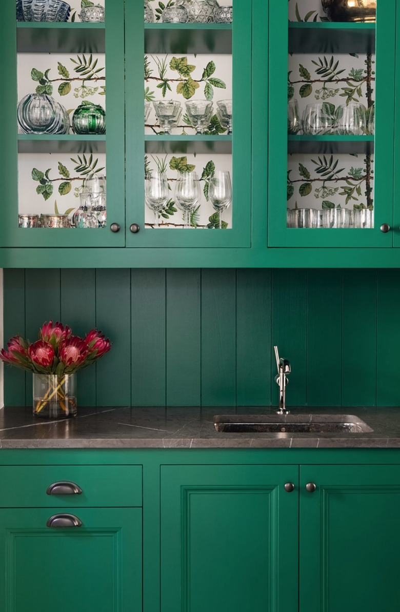 Green kitchen cabinets with wallpaper inside.