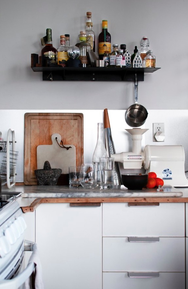 White kitchen with black shelf for bar supplies hanging above counter.