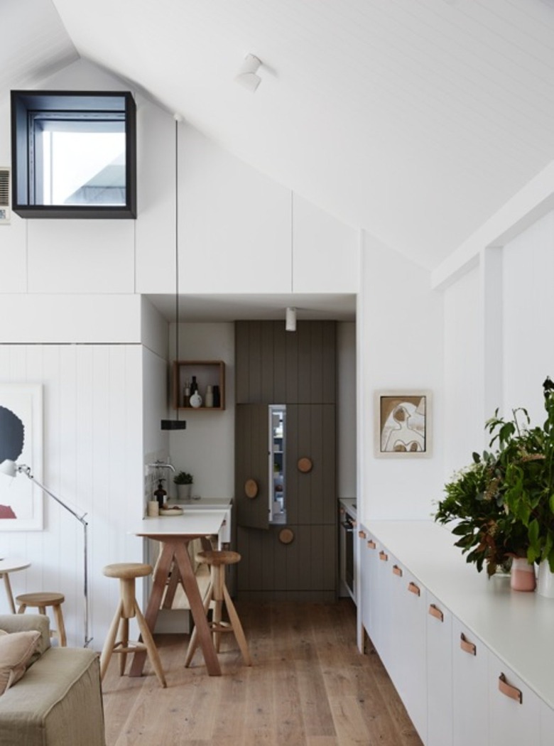 Small kitchen with hidden refrigerator, bar, white cabinets.