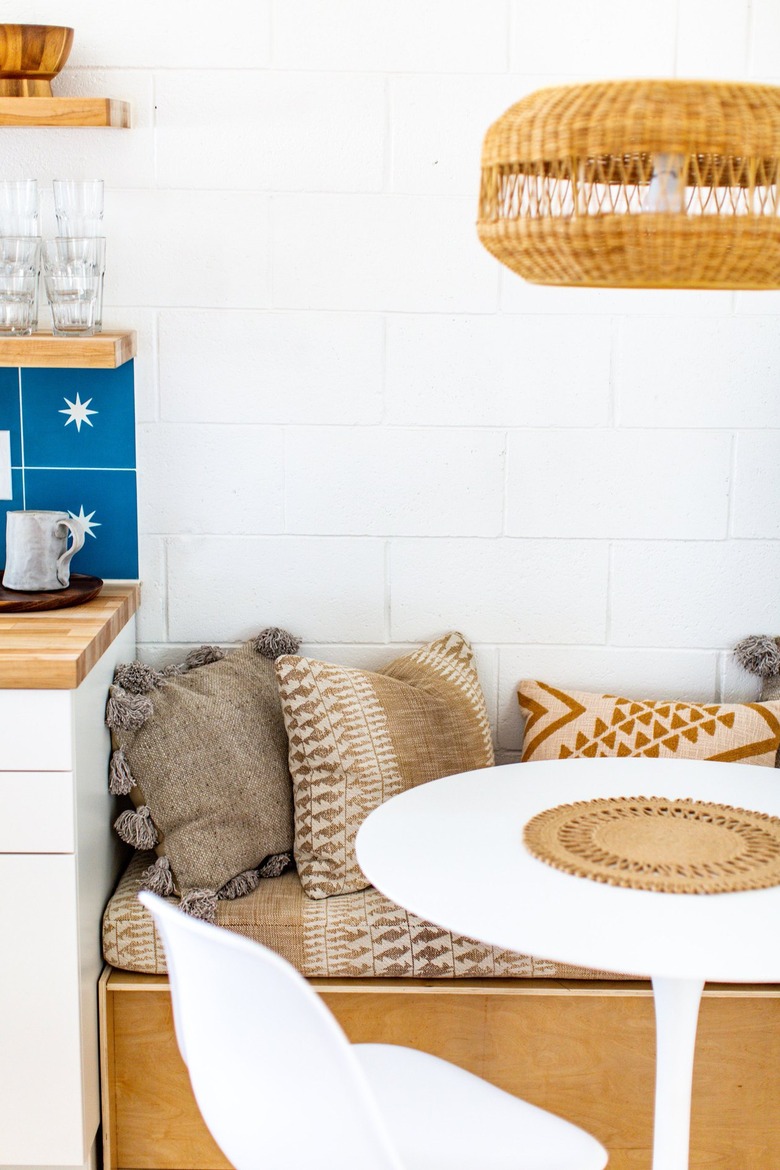 a breakfast nook with a banquette, small round table, and a wicker pendant light