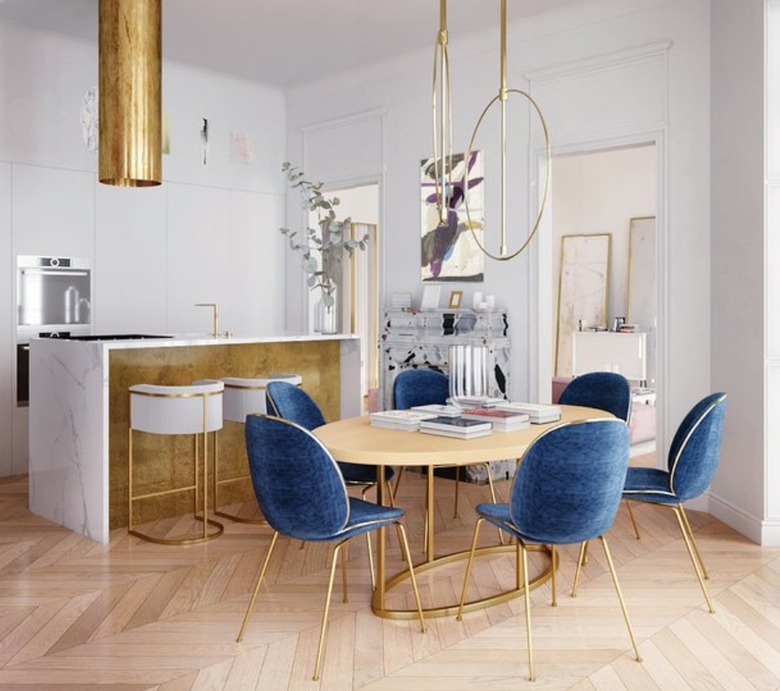 Kitchen with gold hood, gold bar, dining area, chandelier, blue velvet chairs.