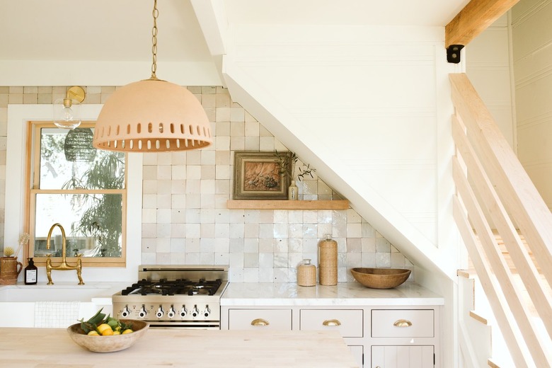 pendant lamp over wooden kitchen island in kitchen with beige tiled backsplash