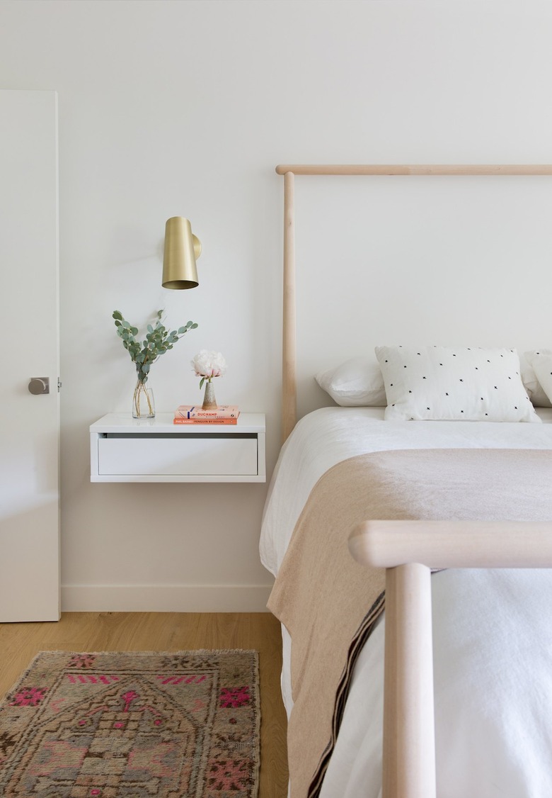 small white bedroom with brass sconce