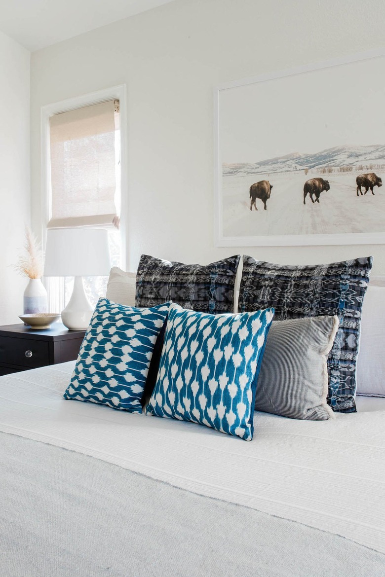 white bed with blue throw pillows in small bedroom