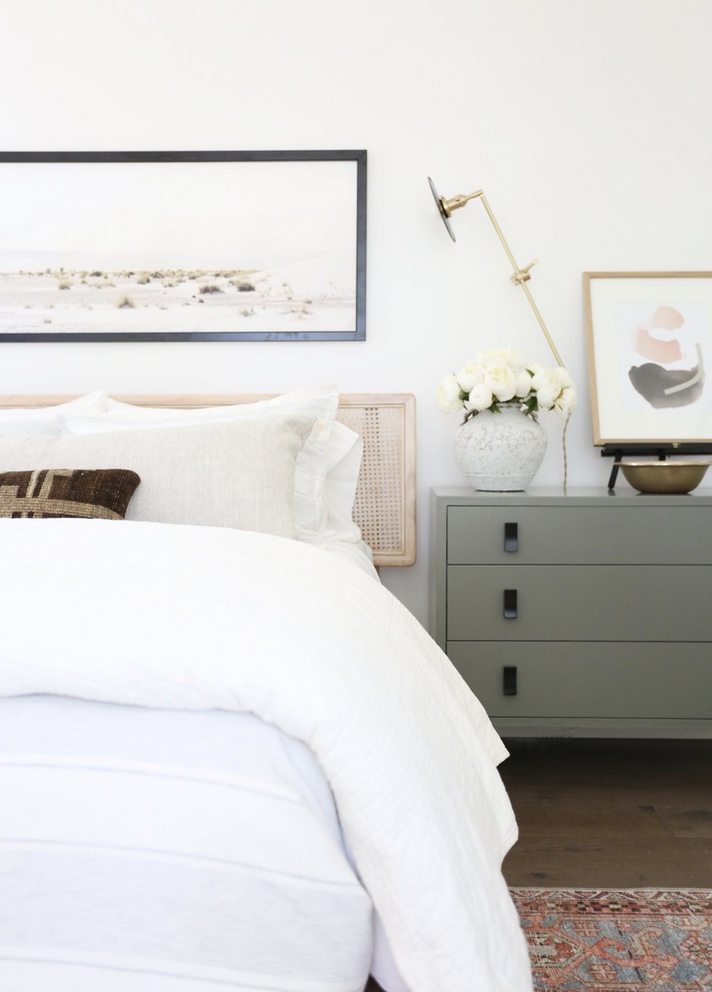 white bed with green dresser in small bedroom